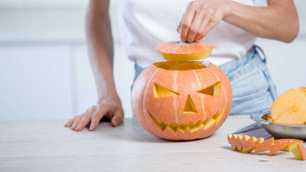istock Orange halloween pumpkin with carved face in white kitchen 1276914417