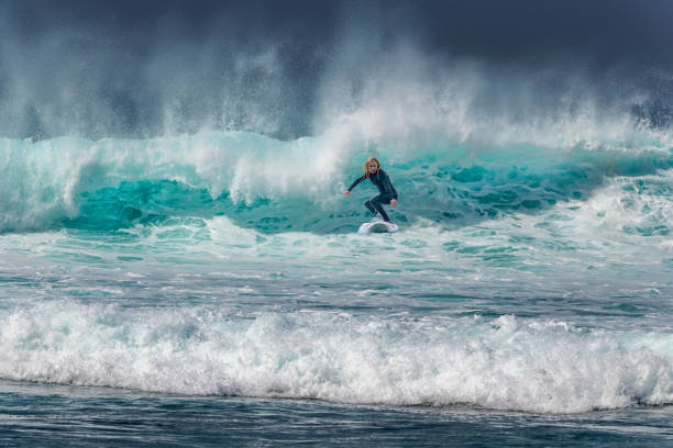 femme surfant sur des vagues à tenerife, playa de las americas, espagne - vague déferlante photos photos et images de collection
