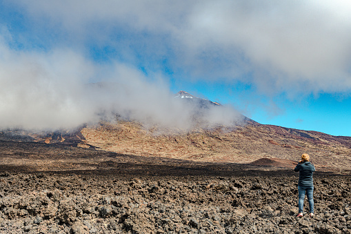 Mature woman photographs a road under the El Teido volcano, Tenerife, Spain,Nikon D850