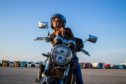 Chica sexy sentada en la motocicleta de estilo retro y la correa del casco de fijación antes de montar. Libertad y moto andando. photo