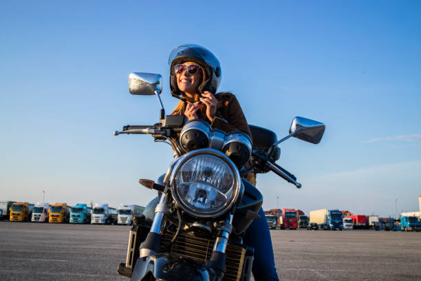 garota sexy sentada em motocicleta estilo retrô e cinto de capacete de fixação antes de montar. liberdade e pilotagem de moto. - motorcycle handlebar road riding - fotografias e filmes do acervo