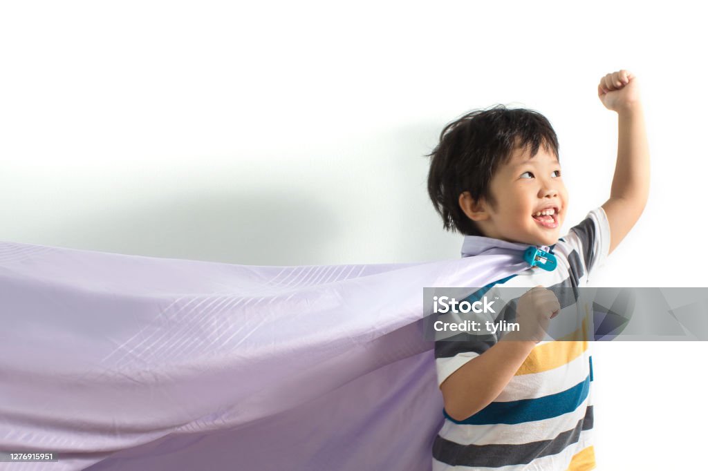 Boy dressed as a superhero Cute little Asian boy with purple cape and dive imitating superhero against white background. Child Stock Photo