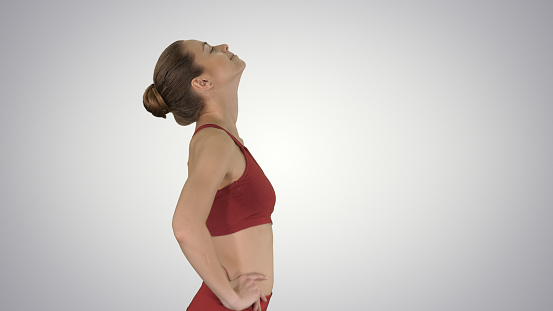 Medium shot. Side view. Female walking and doing neck stretching exercise to release build up tension on gradient background. Professional shot in 4K resolution. 009. You can use it e.g. in your sport, yoga, healthy, commercial video, business, presentation, broadcast