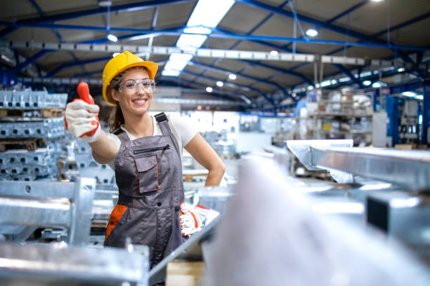 работница производственной линии держит большие пальцы в заводском зале. - manufacturing occupation manual worker factory cheerful стоковые фото и изображения