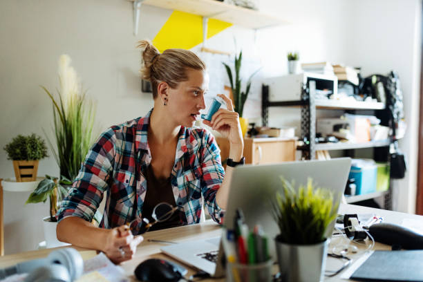 istock Caucasian woman working from home and using asthmatic inhaler 1276921499