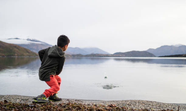 ragazzo che salta pietre nel lago. - throwing people stone tossing foto e immagini stock