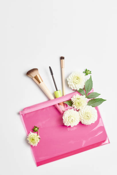 istock a pink cosmetic bag, makeup brushes, and fresh white flowers. flat lay, copy space 1276922980