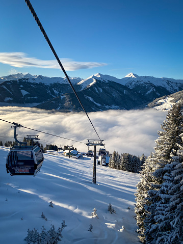 Vorderglemm, Austria - January 30, 2020: Scenic view from Schönleiten cable car ski lift to snow covered mountains and a blanket of clouds in the ski resort of Saalbach-Hinterglemm early in the morning