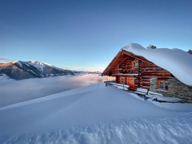 antigua cabaña de montaña cubierta de nieve antigua casa de campo en la región de esquí de saalbach hinterglemm en los alpes austriacos al amanecer - ski resort hut snow winter fotografías e imágenes de stock