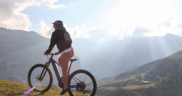 istock Female mountain e-biker rides through alpine meadow 1276929573