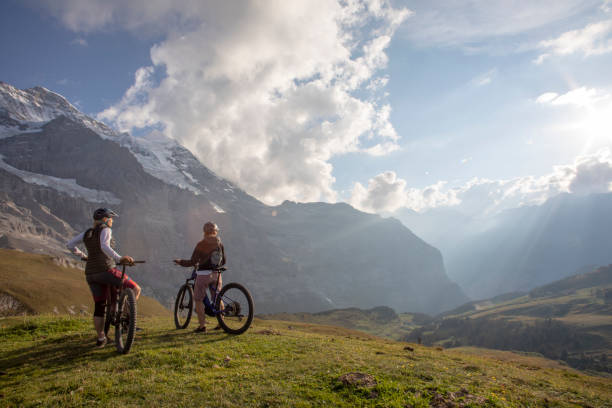 istock Female mountain e-bikers relax in alpine meadow 1276929631