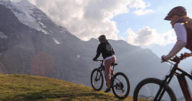 istock Female mountain e-bikers rides through alpine meadow 1276929675