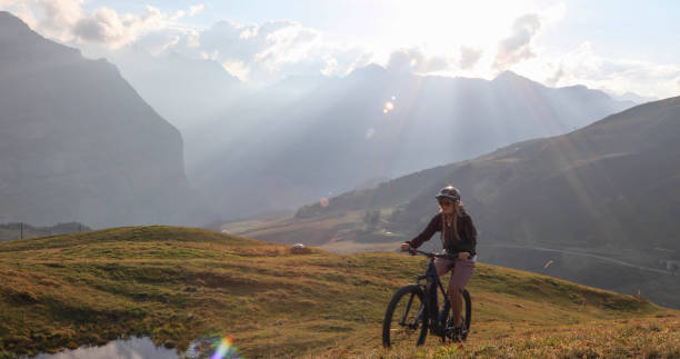 istock Female mountain e-biker rides up alpine meadow 1276930202