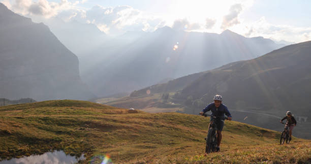 istock Mountain e-bikers rides up alpine meadow 1276930212