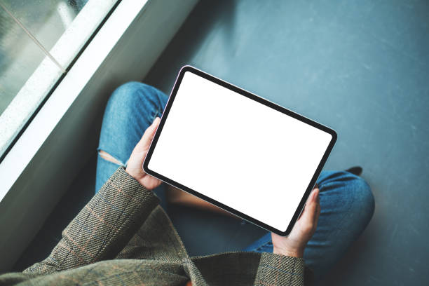 istock a woman holding and using digital tablet with blank white desktop screen while sitting on the floor 1276932784