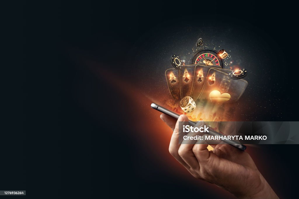 Creative background, online casino, in a man's hand a smartphone with playing cards, roulette and chips, black-gold background. Internet gambling concept. Copy space Creative background, online casino, in a man's hand a smartphone with playing cards, roulette and chips, black-gold background. Internet gambling concept. Copy space. Casino Stock Photo