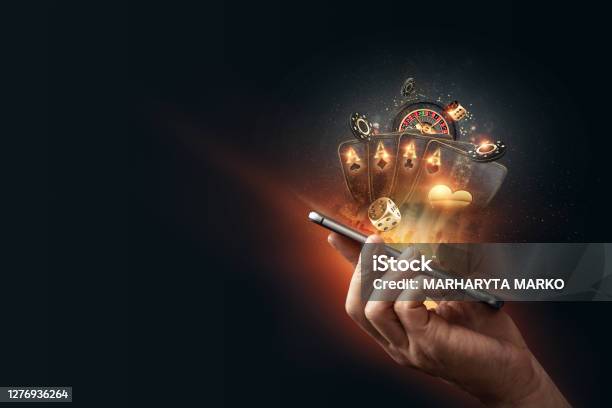 Creative Background Online Casino In A Mans Hand A Smartphone With Playing Cards Roulette And Chips Blackgold Background Internet Gambling Concept Copy Space Stock Photo - Download Image Now