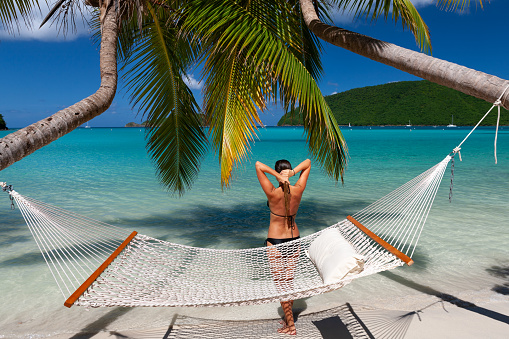 woman standing next to hammock on a perfect tropical beach in the Caribbean, Maho Bay, St. John