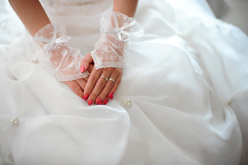 Close up image of bride hands resting on her wedding dress