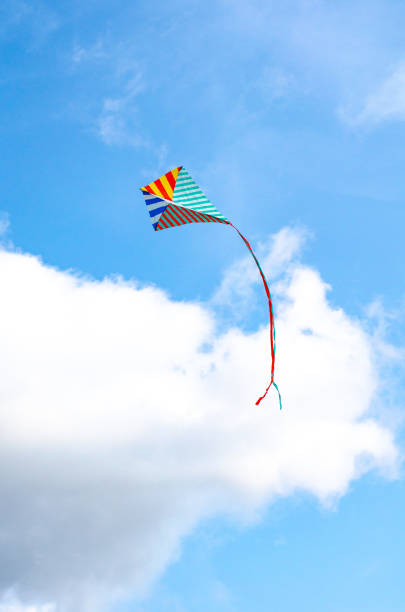 istock Multi-colored kite on a blue sky background with white clouds. Symbol of peace, freedom and serenity. copy cpase, place for text. 1276940910
