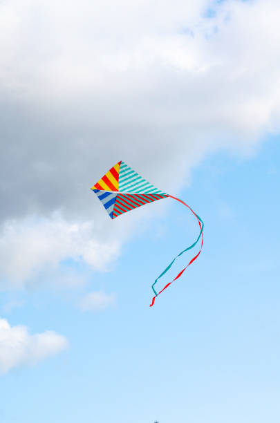 istock Multi-colored kite on a blue sky background with white clouds. Symbol of peace, freedom and serenity. copy cpase, place for text. 1276940912