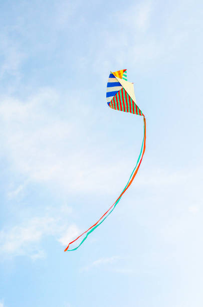 istock Multi-colored kite on a blue sky background with white clouds. Symbol of peace, freedom and serenity. copy cpase, place for text. 1276940920