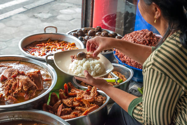 The gudeg food Jogjakarta, Indonesia - September 22, 2017: the "Gudeg" seller picking some menus to be placed in a plate along with the rice, it was lunchtime. Gudeg is a famous traditional Jogjakarta food gudeg stock pictures, royalty-free photos & images