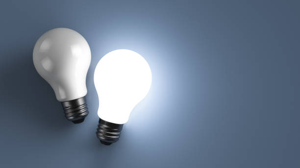 istock Two energy saving light bulbs on the table. One of them glows. 1276949028