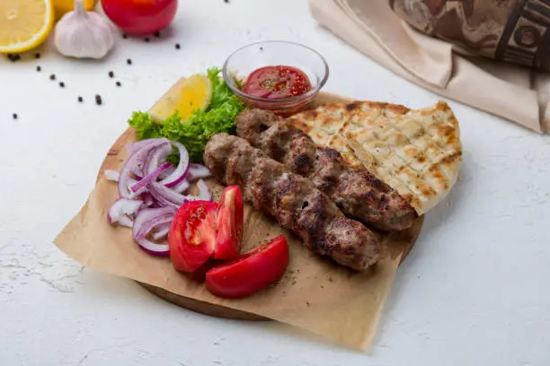 Lamb Lula kebab on the board with sause and pita, greek style kitchen
