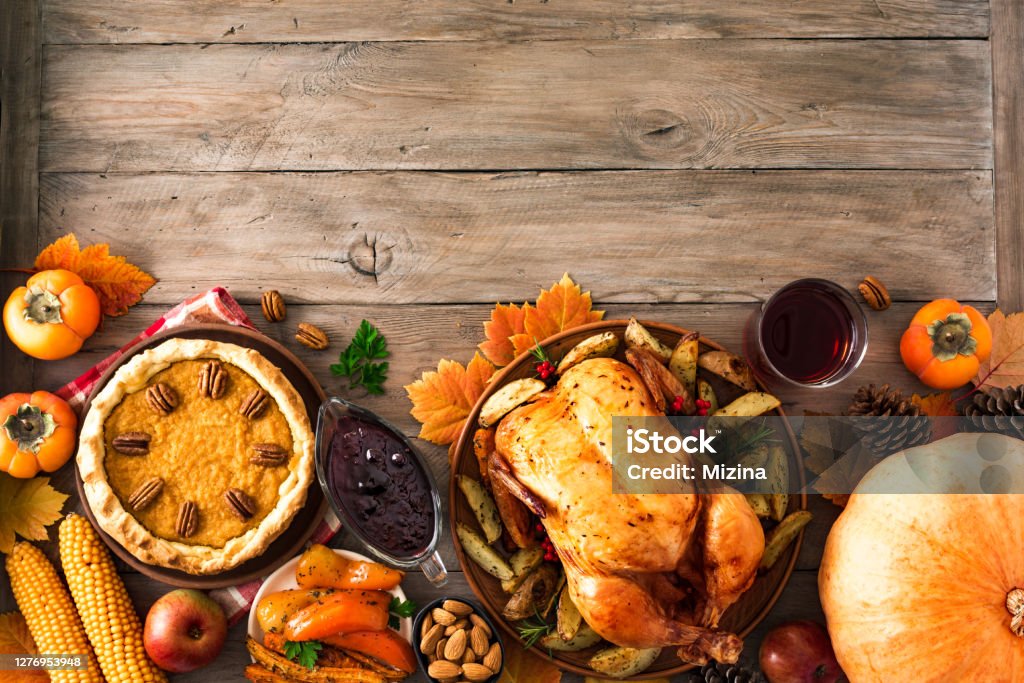 Thanksgiving Turkey Dinner Thanksgiving dinner with chicken, cranberry sauce, pumpkin pie, wine, seasonal vegetables and fruits on wooden table, copy space. Traditional autumn holiday food concept. Thanksgiving - Holiday Stock Photo