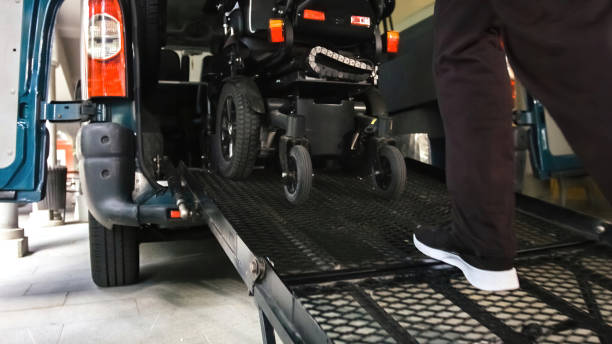 Disabled person on wheelchair using van ramp Wheelchair going into vehicle using ramp. Driver is helping to push it up. wheelchair lift stock pictures, royalty-free photos & images