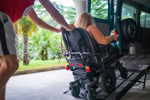 Disabled person on wheelchair using van ramp Woman on wheelchair using a vehicle ramp. Accessible transport with assistant driver. wheelchair lift stock pictures, royalty-free photos & images