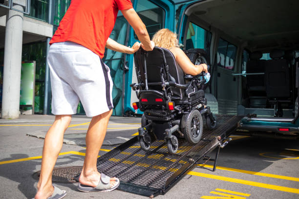 Disabled person on wheelchair using van ramp Woman on wheelchair using a vehicle ramp. Accessible transport with assistant driver. wheelchair lift stock pictures, royalty-free photos & images