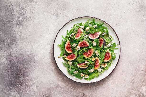 Fresh diet salad figs, arugula and blue cheese in a plate on a rustic beige background. Top view, flat lay, copy space. Fresh diet salad figs, arugula and blue cheese in a plate on a rustic beige background. Top view, flat lay, copy space plate fig blue cheese cheese stock pictures, royalty-free photos & images