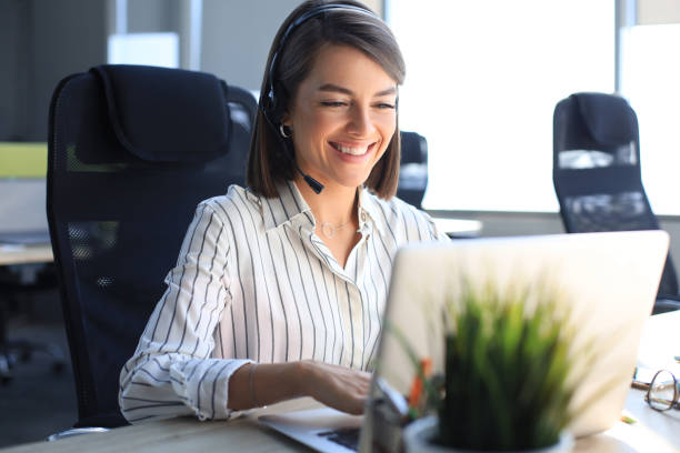 istock Beautiful smiling call center worker in headphones is working at modern office 1276965711