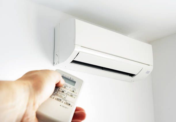 Young man holding a remote control air conditioner in the house