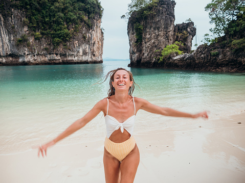 Happy travel female running on beautiful white sand beach in Thailand enjoying tropical vacations
