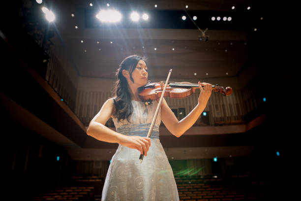 violinista femenina tocando el violín en la sala de conciertos - violinista fotografías e imágenes de stock