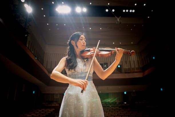 female violinist playing the violin in concert hall - violinista imagens e fotografias de stock