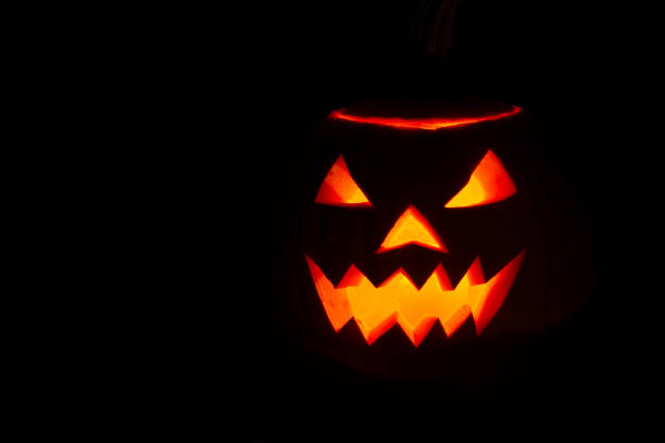 istock halloween pumpkin on a tree stump on a dark night 1276975312