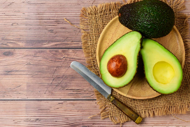 istock Avocado half on wood plate on wood background and copy space. 1276975574