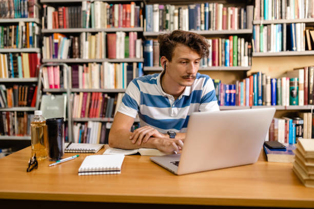 istock Hardworking University student surfing the net on his laptop while collecting information for his research 1276977004