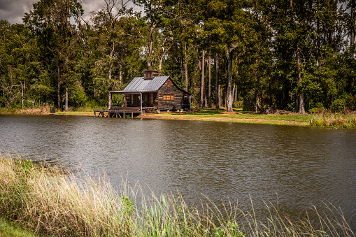 Expanse view of the exterior of a rural rustic wooden camp house used for fishing and hunting. The house is located on a large pond