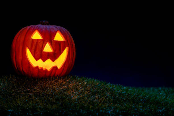istock A smiling Jack O’ Lantern sitting in the grass at night for Halloween, 1276977995