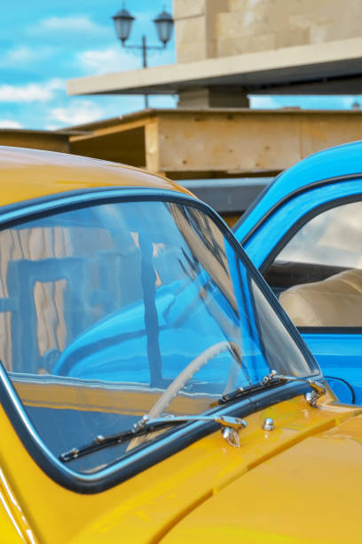 kaptur samochodu i przednia szyba żółtego samochodu na tle niebieskiego samochodu z bliska - hood car headlight bumper zdjęcia i obrazy z banku zdjęć