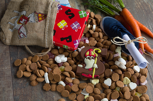 Dutch candy called Pepernoten eaten during Sinterklaas feast. Beside it presents for the kid and the shoe of the kid with carrots and a drawing