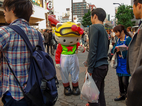 Asakusa, Tokyo / Japan - May 18th, 2014: Human dressed as hello kitty on the streets of Asakusa. Japanese and asian tourists waving and mesmerized by the adult size cartoon cat character