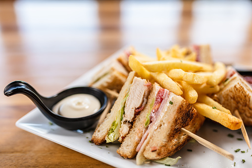 Delicious club sandwich served with french fries