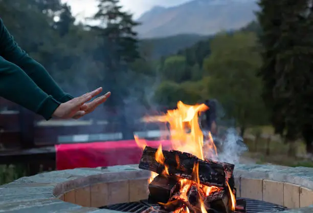 Photo of man warming his hands by the fire at dusk