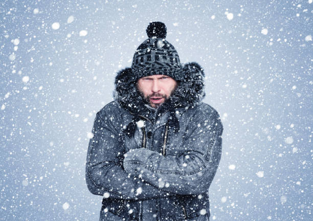 Frozen bearded man in winter clothes warms his hands, cold, snow, frost, blizzard Frozen bearded man in winter clothes warms his hands, cold, snow, frost, blizzard warms stock pictures, royalty-free photos & images